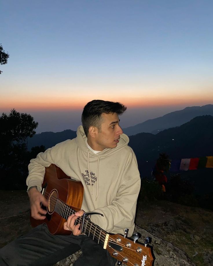 Anuv Jain playing guitar in the mountains at sunset